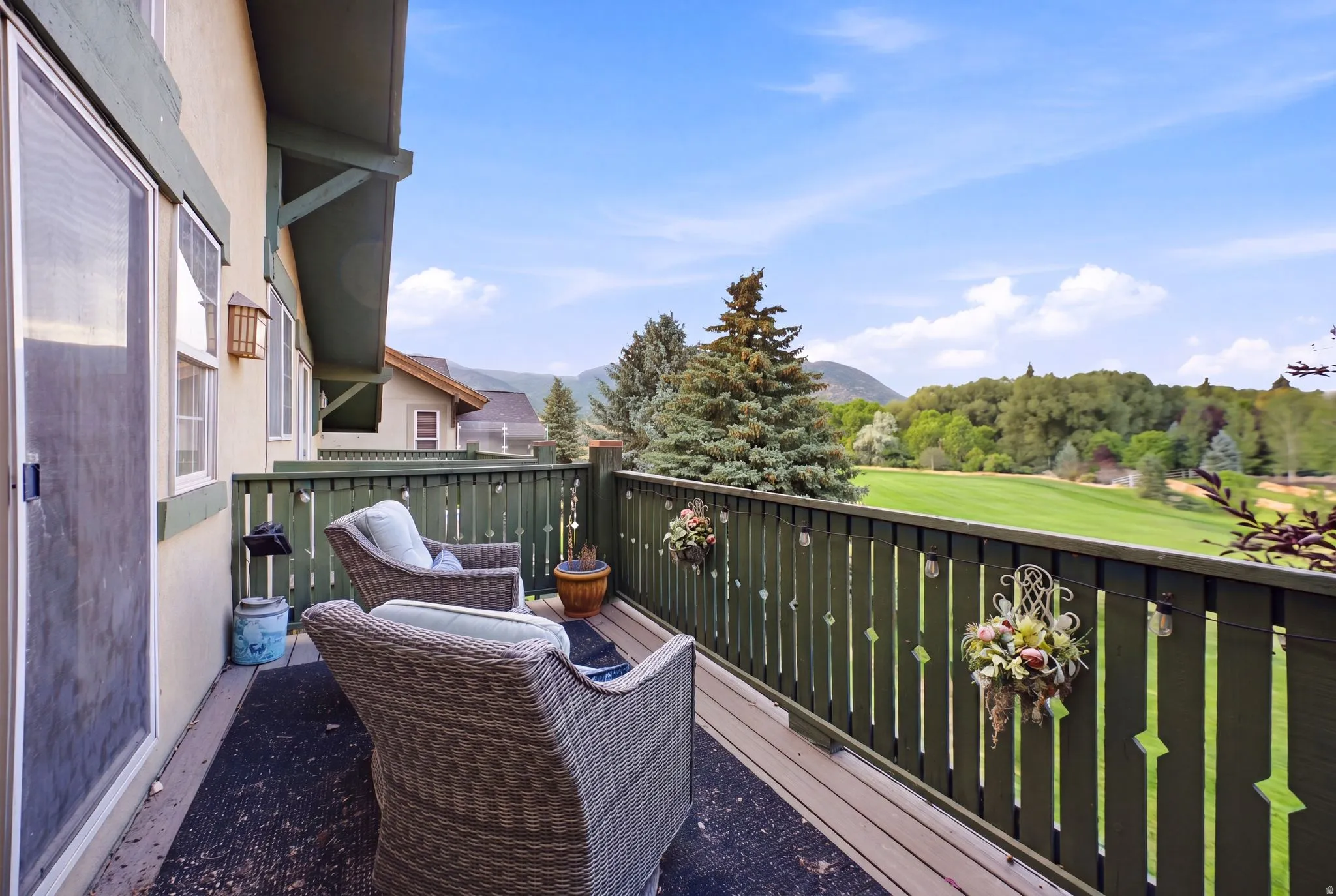 Exterior deck featuring a green wood balustrade, wood-plank flooring, and a sliding glass door entry