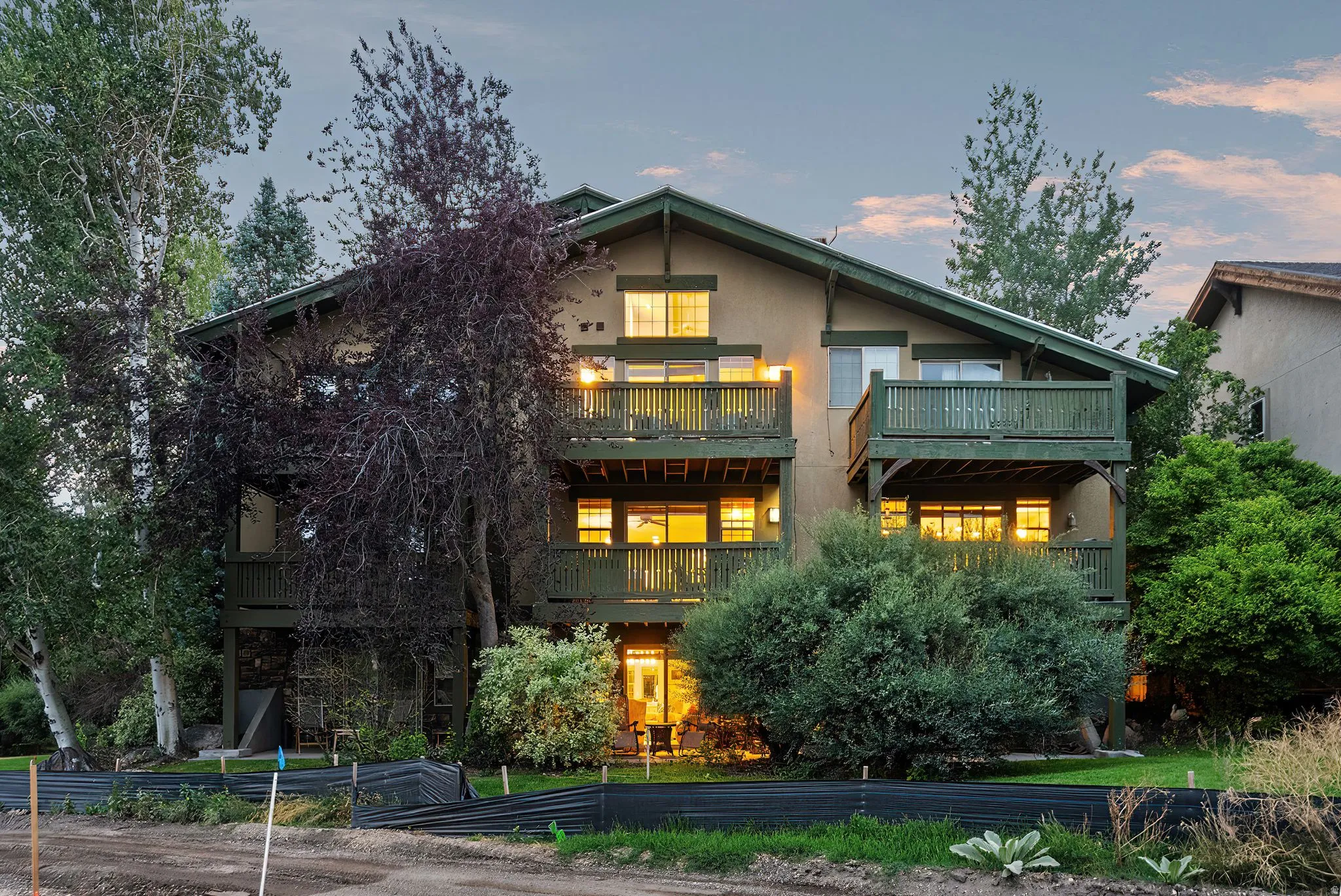 Multi-level stucco exterior featuring multiple balconies with wood railings, a sloped roofline, and mature landscaping