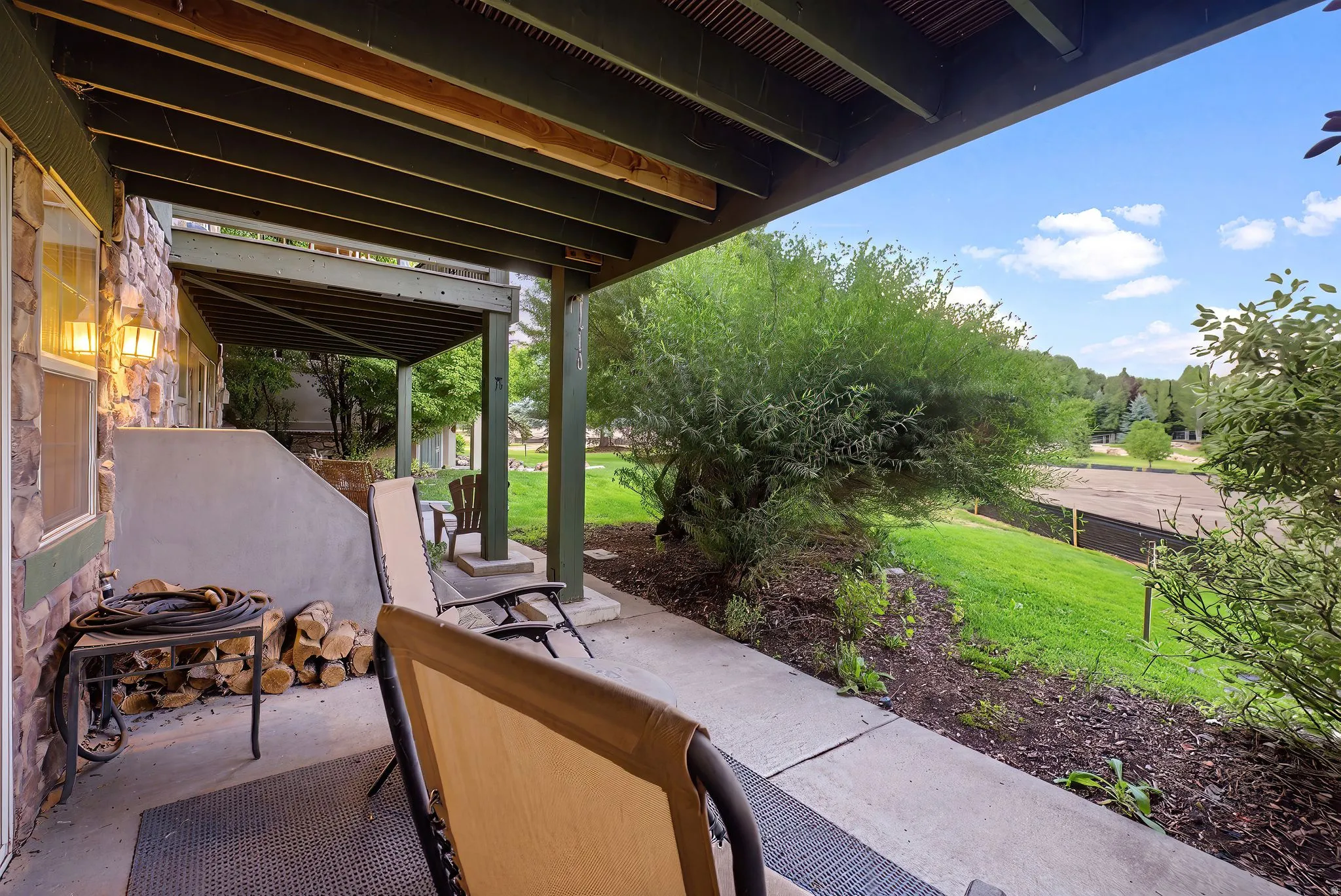 Covered patio featuring a stone-clad exterior, concrete flooring, and an overhead deck structure