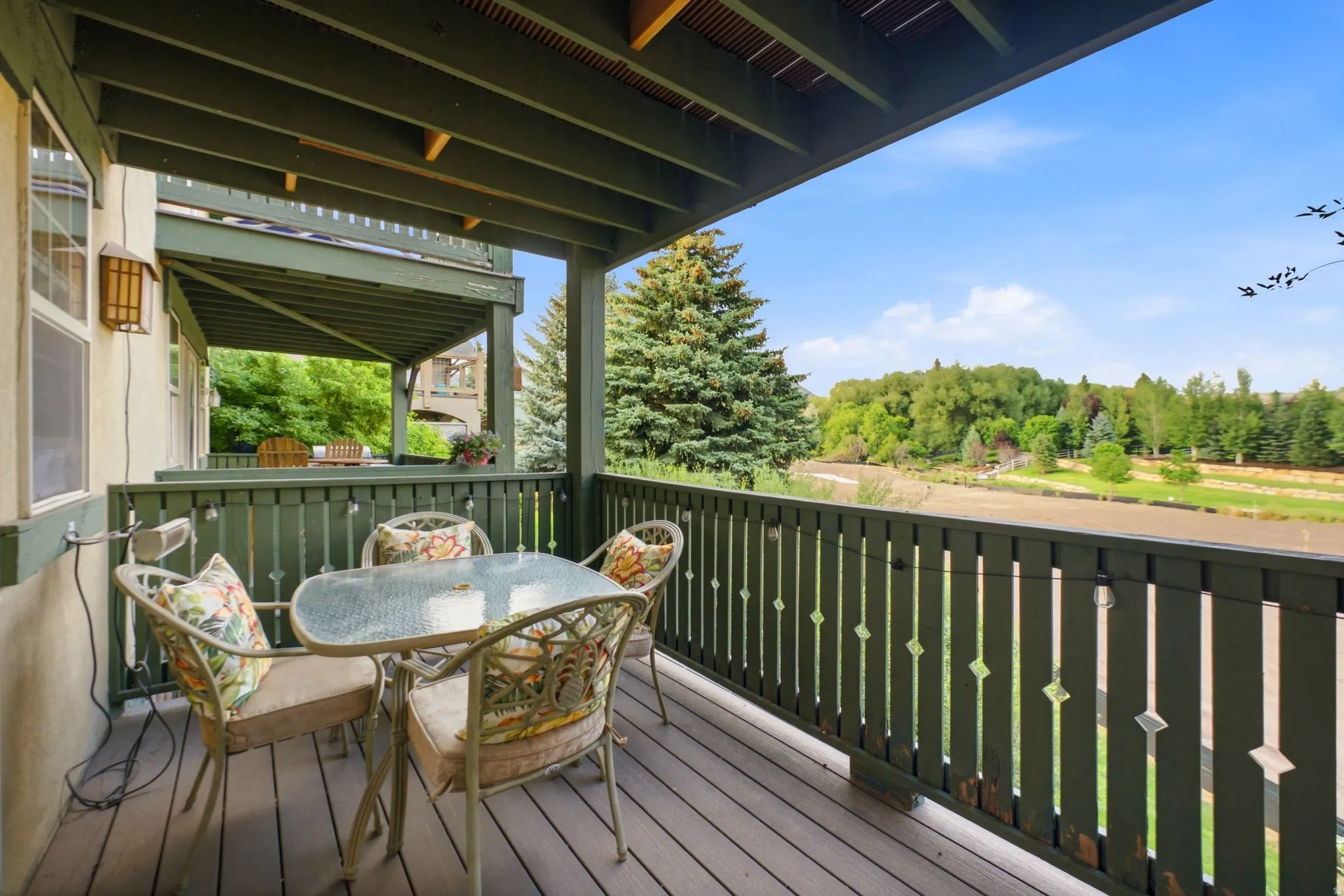 Outdoor deck featuring composite decking, painted wood railing with decorative cutouts, and an exterior wall light fixture