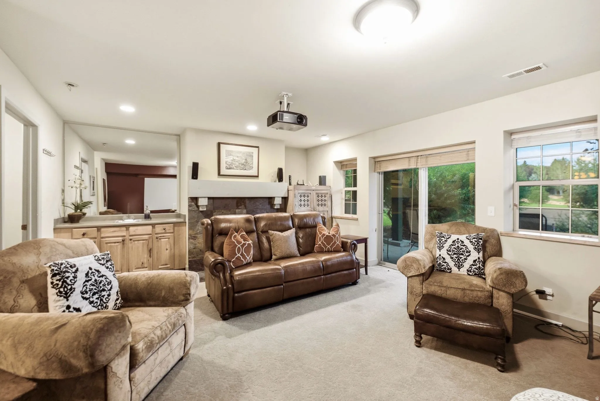 Living area featuring a stone-clad fireplace, built-in wet bar with wood cabinetry, recessed lighting, and a sliding glass door