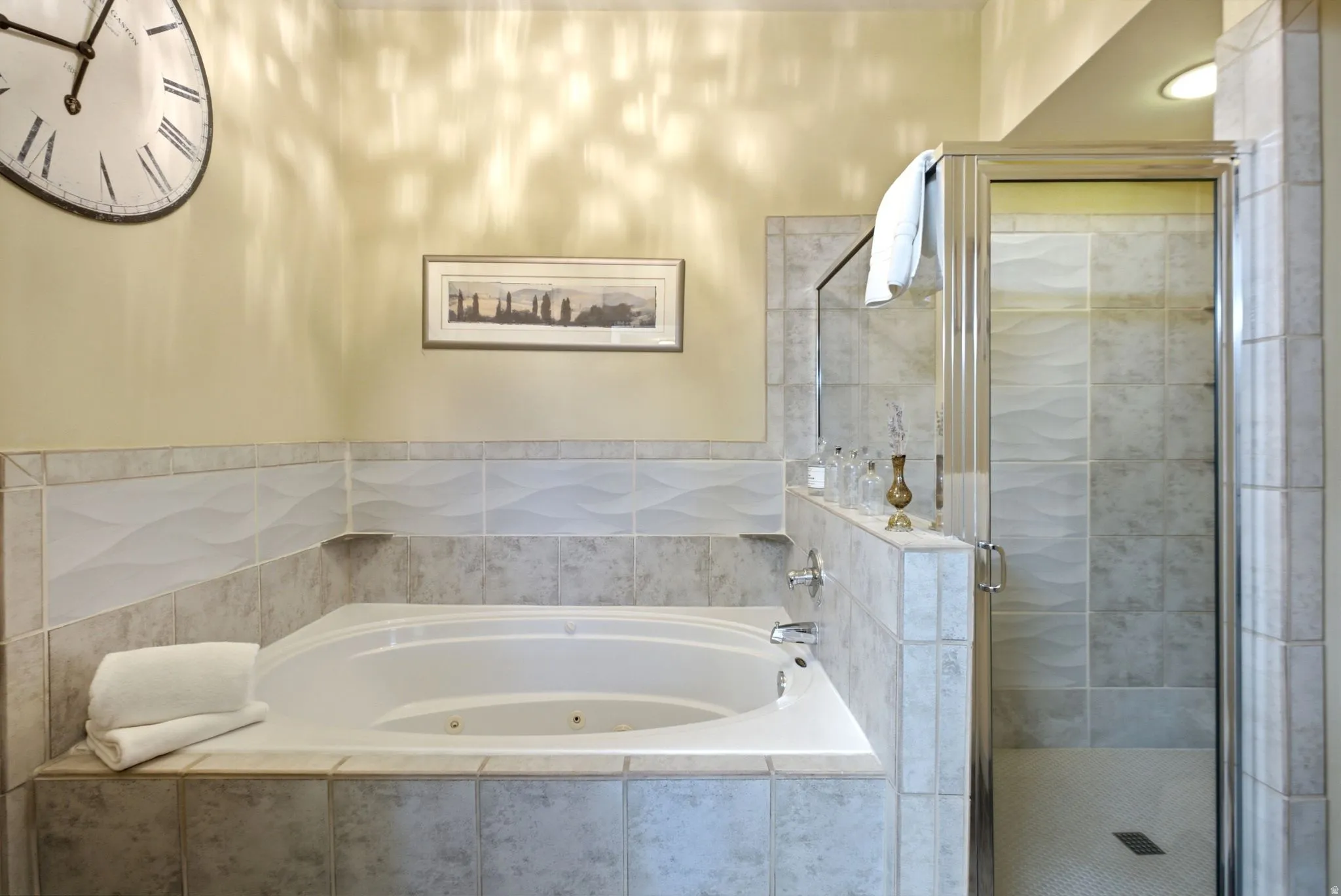 Corner soaking tub and a glass-enclosed shower featuring tile surrounds