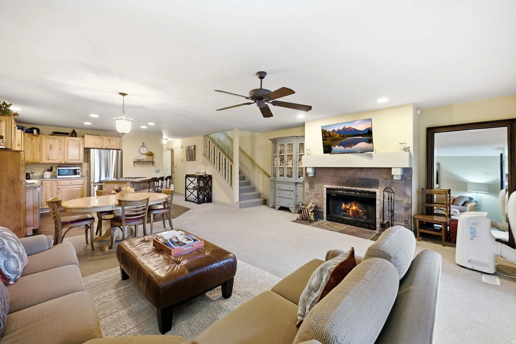 Living area with a stone-surround fireplace, mantel, and ceiling fan