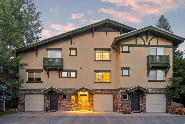 Multi-level stucco exterior with stone accents and a dark green trim