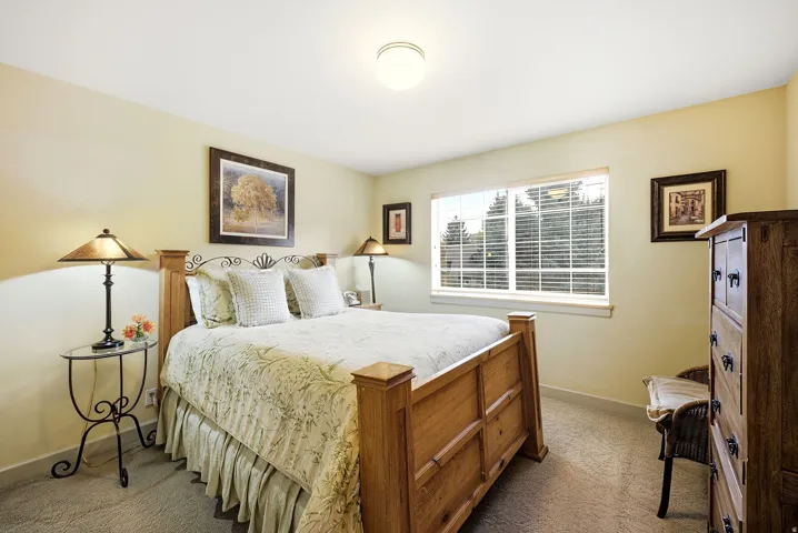 Bedroom featuring a window with blinds, light tan walls, and carpet flooring