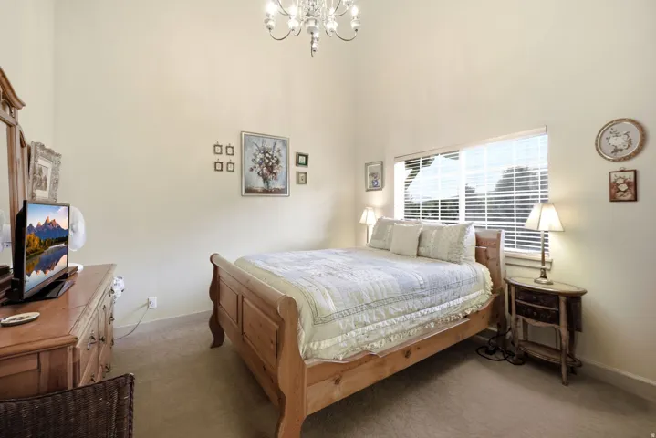 Room with vaulted ceiling, featuring a window with horizontal blinds, neutral wall paint, and carpeted flooring