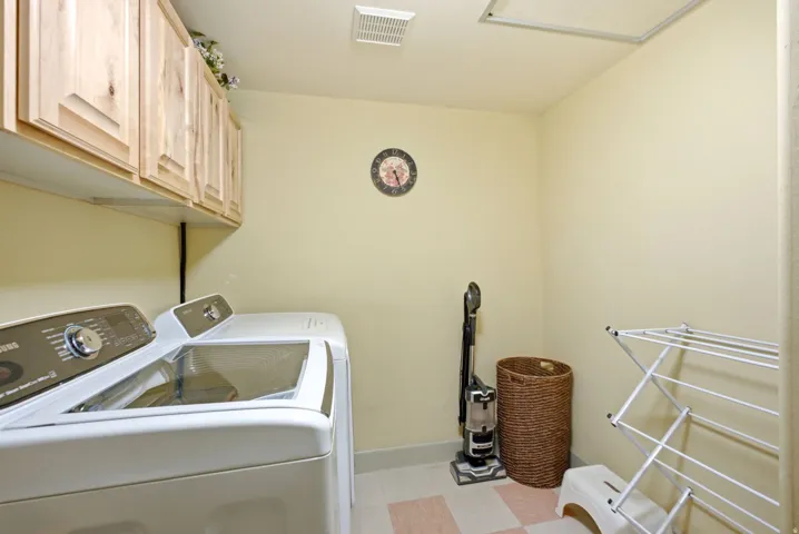 Laundry area featuring wood-finish cabinetry, light-toned wall paint, and tiled flooring