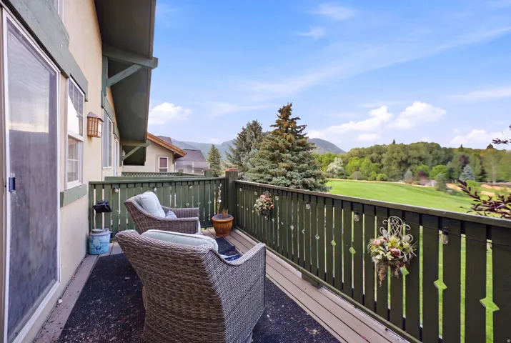 Exterior deck featuring a green wood balustrade, wood-plank flooring, and a sliding glass door entry