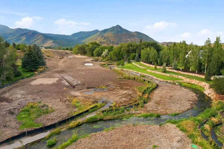 Expansive property featuring a winding stream, terraced landscaping with stone retaining walls, and mature trees