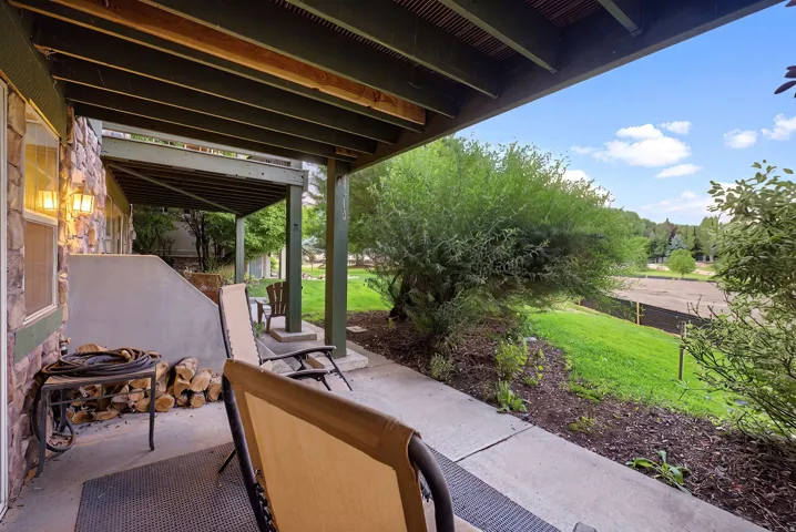 Covered patio featuring a stone-clad exterior, concrete flooring, and an overhead deck structure