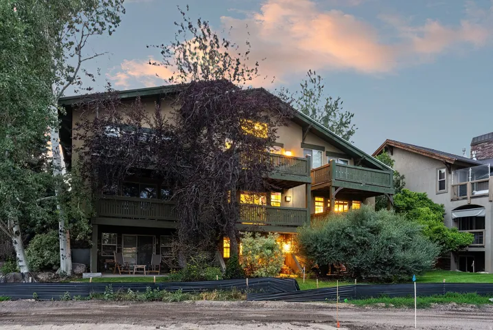 Multi-level residence featuring a stucco exterior and multiple recessed balconies with wood railings