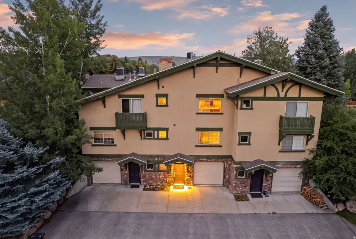 Multi-level stucco exterior with dark green trim and exposed rafter tails