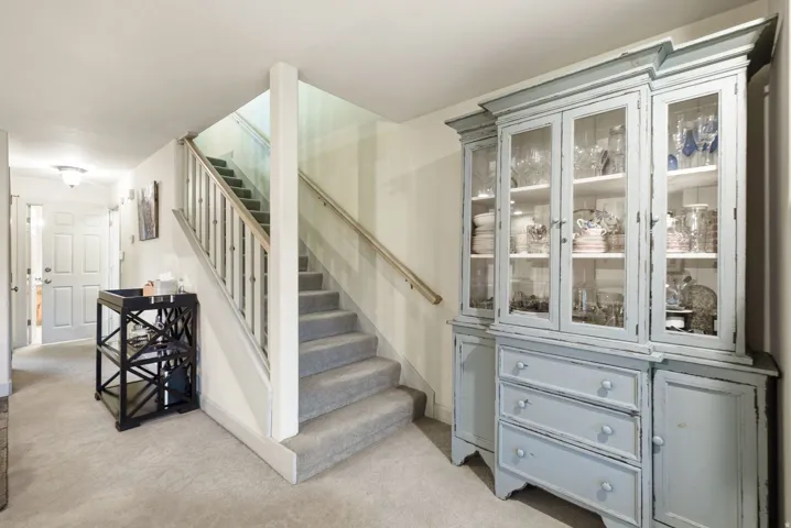 Carpeted staircase with white balusters and wood handrail