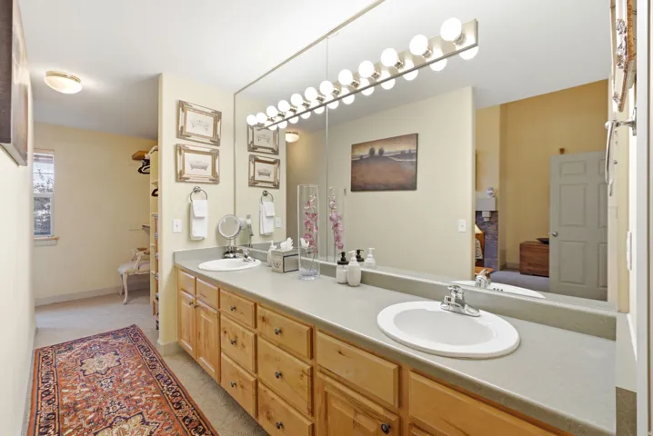 Double vanity featuring wood cabinetry, integrated sinks, and a large wall-mounted mirror with overhead lighting