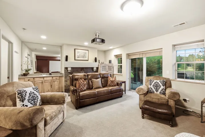 Living area featuring a stone-clad fireplace, built-in wet bar with wood cabinetry, recessed lighting, and a sliding glass door