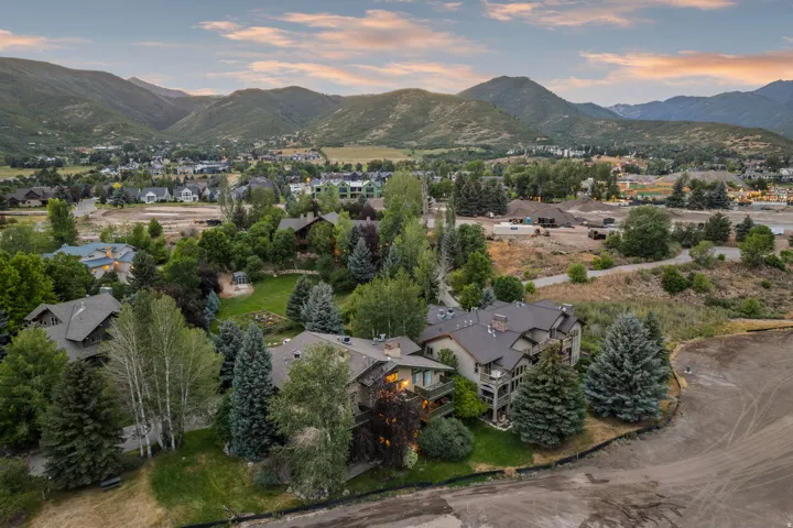 Expansive property featuring mature trees and established landscaping, surrounded by mountainous terrain