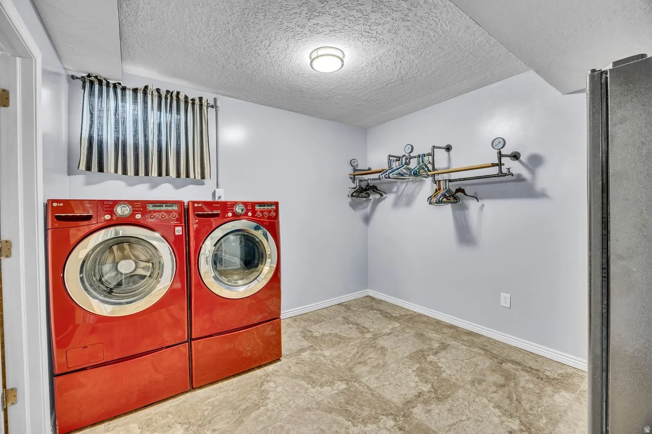 Dedicated laundry area featuring front-loading appliances, light grey walls, and patterned tile flooring