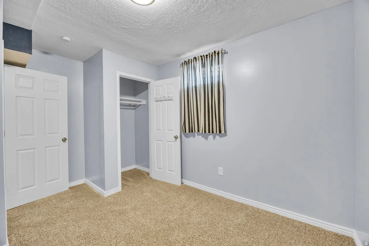 Carpeted room with light blue walls, white paneled doors, and a built-in closet featuring a hanging rod