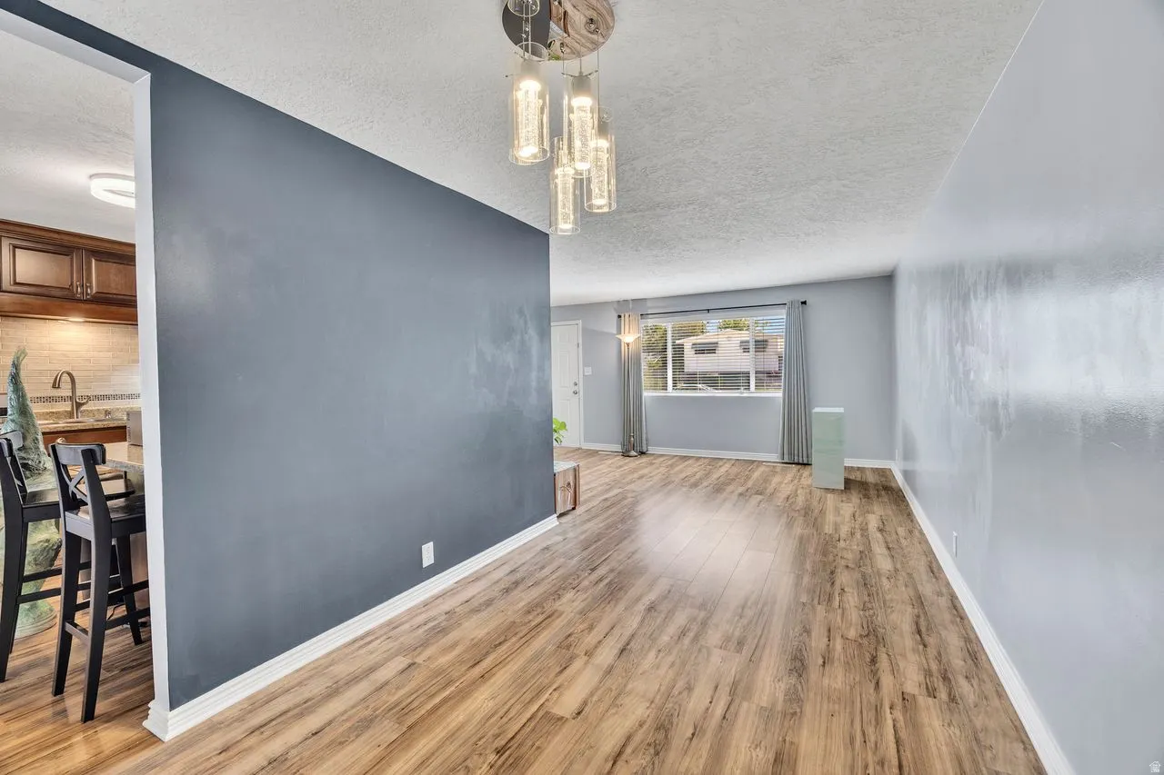 Open-concept living space featuring wood-finish flooring, a modern chandelier, and light blue wall tones