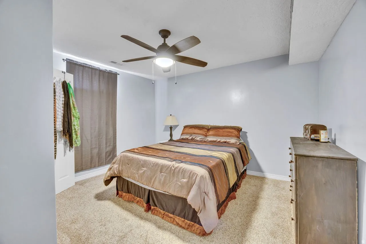 Carpeted room with a ceiling fan light fixture, light blue walls, and a window with blinds