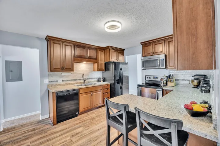 Functional kitchen featuring wood-finish cabinetry, light-toned countertops, and stainless steel appliances