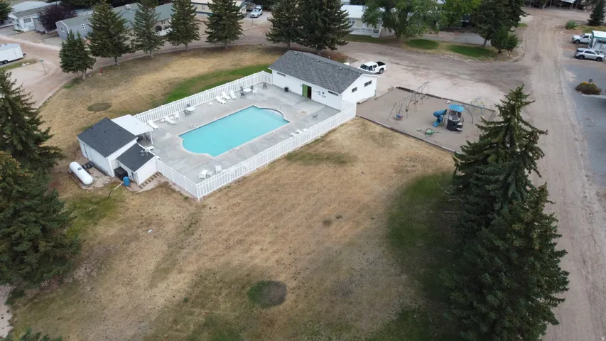 Outdoor swimming pool with surrounding concrete patio, white picket fencing, and multiple lounge chairs