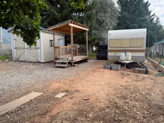 Gravel ground cover featuring a wood deck with railings and an attached shed