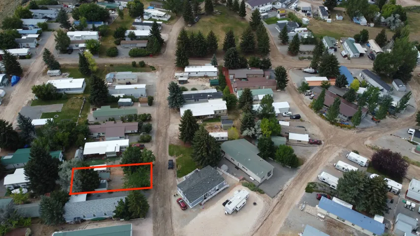 Aerial perspective of a multi-unit property, featuring several residential structures and extensive unpaved pathways