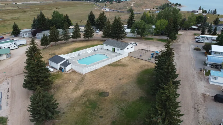 Community pool with surrounding white fencing and nearby recreational area