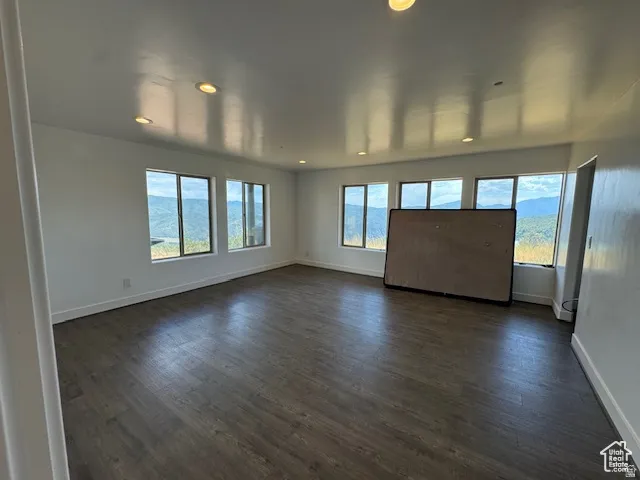 Spacious interior featuring multiple large windows, wood-finish flooring, white baseboards, and recessed lighting