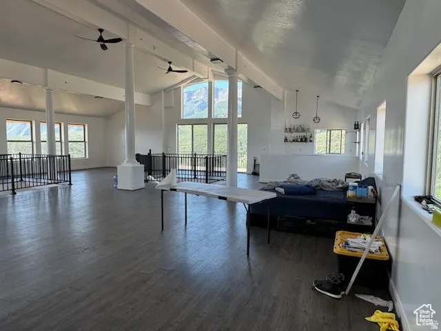 Expansive open-concept room featuring wood-finish flooring, vaulted ceilings, and multiple large windows