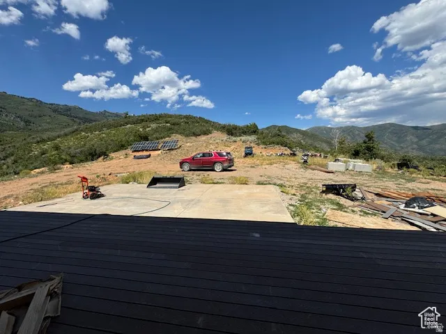 Expansive exterior lot featuring a large concrete pad, multiple solar panel arrays on the hillside, and a broad mountain backdrop