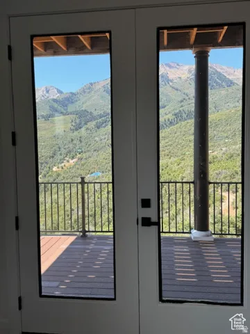 White French doors with dark hardware open onto a deck with a dark railing