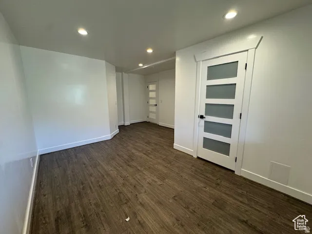 Spacious room featuring wood-finish flooring, white walls, and recessed lighting