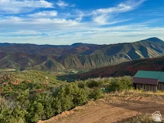 Rustic cabin with a green metal roof and wood siding, situated on a sloped terrain
