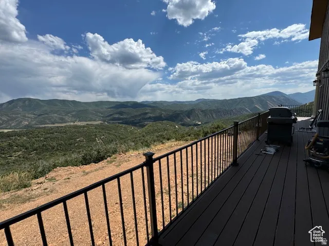 Spacious exterior deck with dark composite decking and black metal railing, overlooking expansive mountain and valley scenery