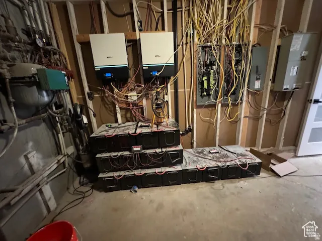Utility room with exposed wood framing, multiple electrical panels, and visible wiring infrastructure