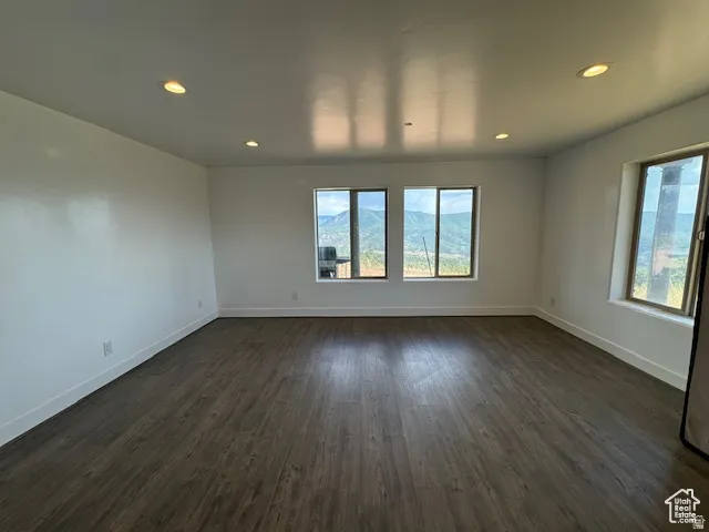 Spacious room featuring wood-finish flooring, recessed lighting, and multiple windows showcasing mountain scenery