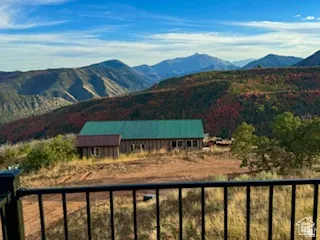 Mountain-facing property featuring a green metal roof, wood-sided exterior, and a black wrought-iron railing