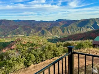 Expansive mountain terrain featuring diverse foliage and a distant structure with a green roof