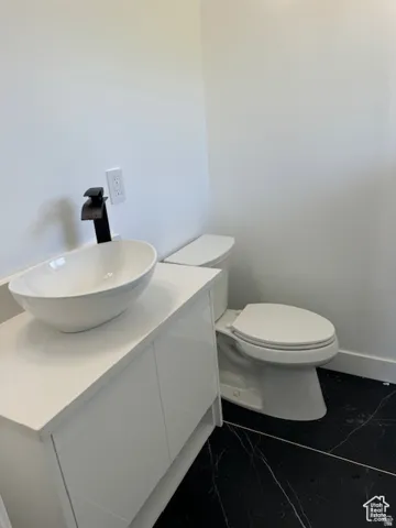 Modern bathroom featuring a white vessel sink, matte black faucet, and white high-gloss vanity with a solid surface countertop