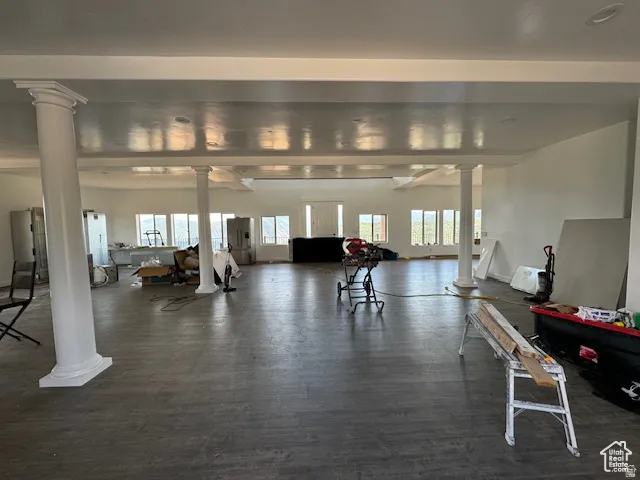 Spacious open-concept room featuring multiple windows, recessed ceiling details, and decorative columns