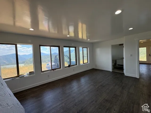 Expansive room featuring dark wood-finish flooring, recessed lighting, and white walls