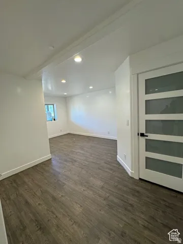 Interior room featuring wood-finish flooring, recessed lighting, white baseboards, and a contemporary door with frosted glass panels and matte black hardware
