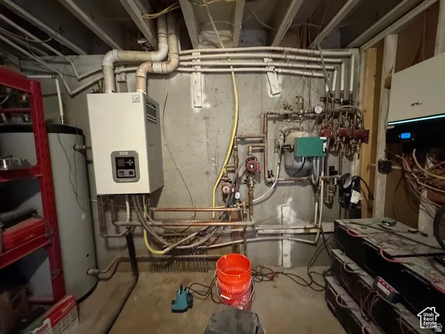 Utility room featuring a tankless water heater, hot water storage tank, and comprehensive plumbing system with multiple circulation pumps and associated piping