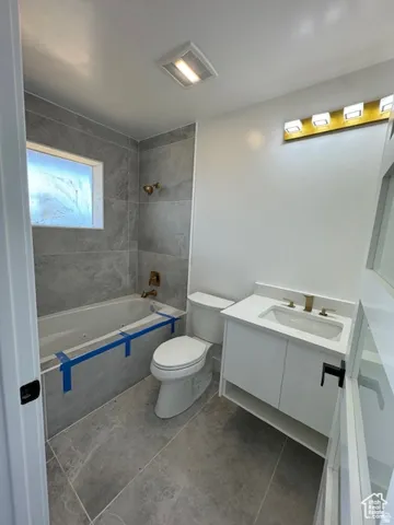 Bathroom featuring a white vanity with an integrated sink, gold-toned faucet, and a corresponding gold-toned light fixture