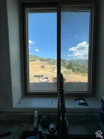 Kitchen window with a sliding panel, providing expansive hillside and mountain scenery