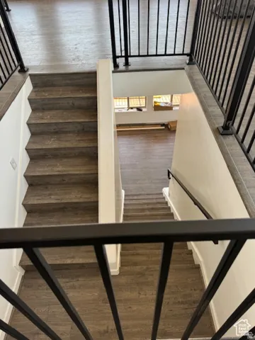 Split-level staircase featuring wood-finish flooring, white risers, and black metal railings