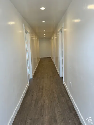 Hallway featuring wood-finish flooring, recessed lighting, and crisp white walls