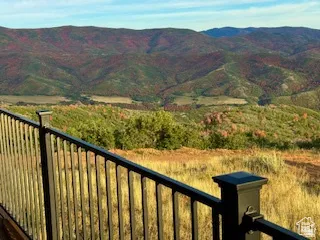 Deck with black metal railing overlooking expansive mountain and valley scenery